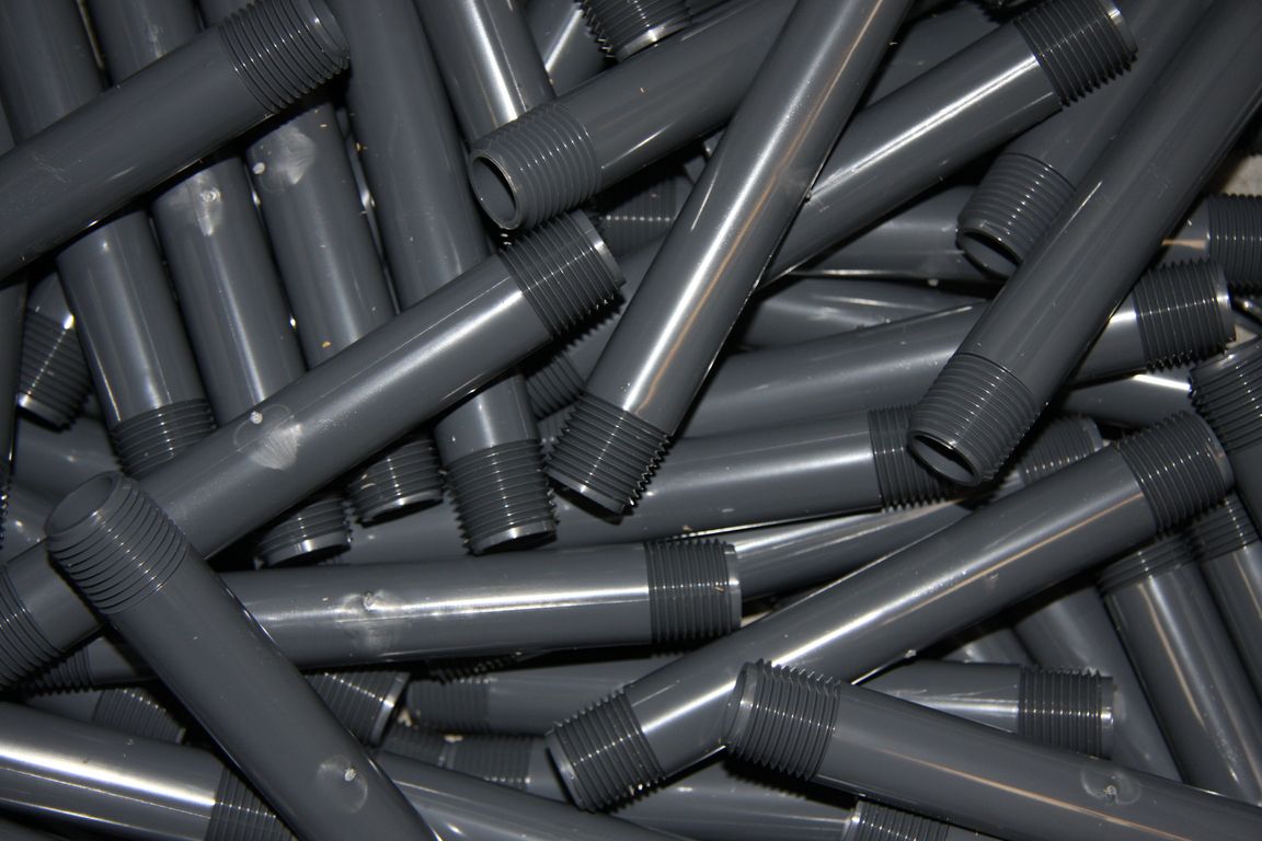 Gray PVC pipe nipples with NPT threaded ends in bulk